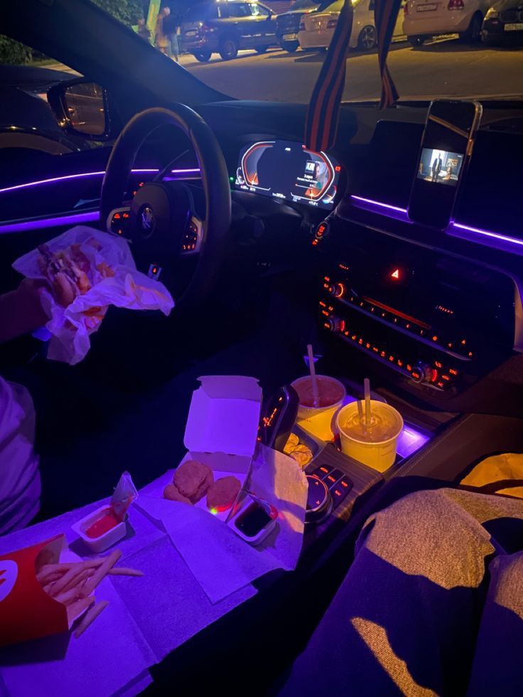 the interior of a car with food and drinks on the table in front of it