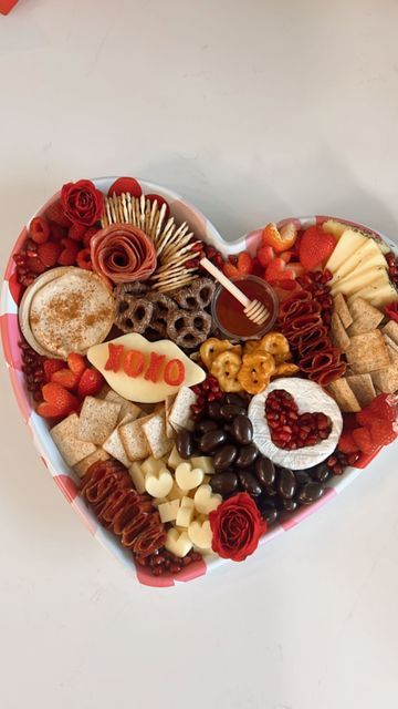 a heart shaped platter filled with assorted snacks and desserts for valentine's day