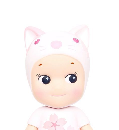 a small doll with a pink dress and cat ears on it's head, sitting in front of a white background