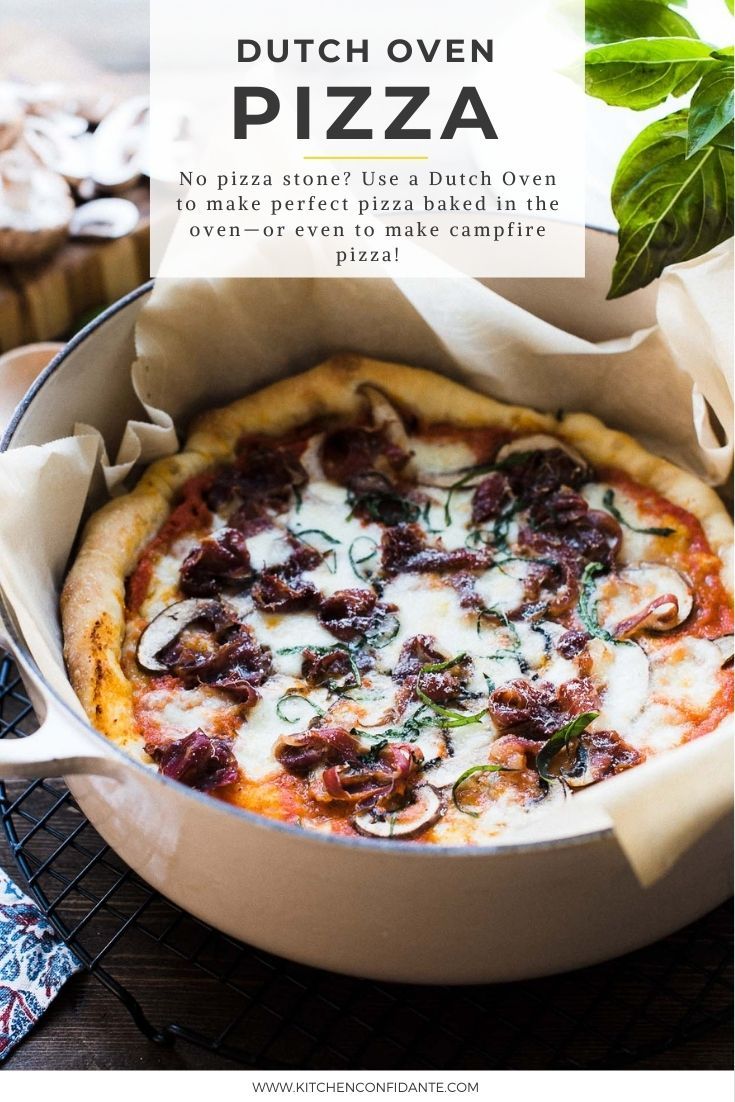 a pizza sitting in a pan on top of a table next to a green leafy plant