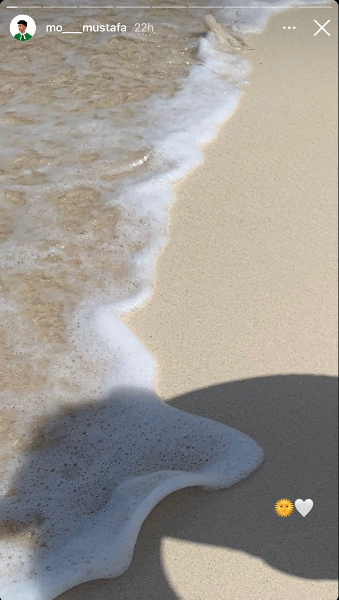 the shadow of a person's hand is casting a heart in the sand at the beach