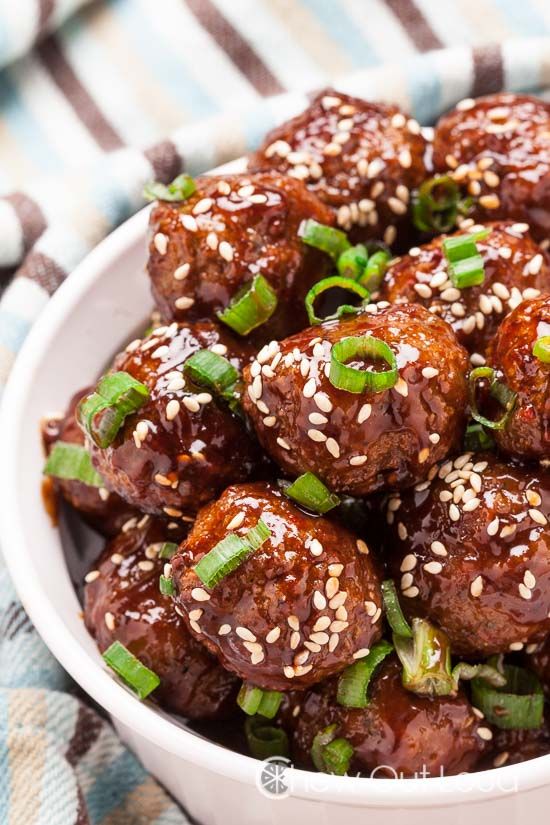 a white bowl filled with meatballs covered in sesame seeds and green onion sprinkles