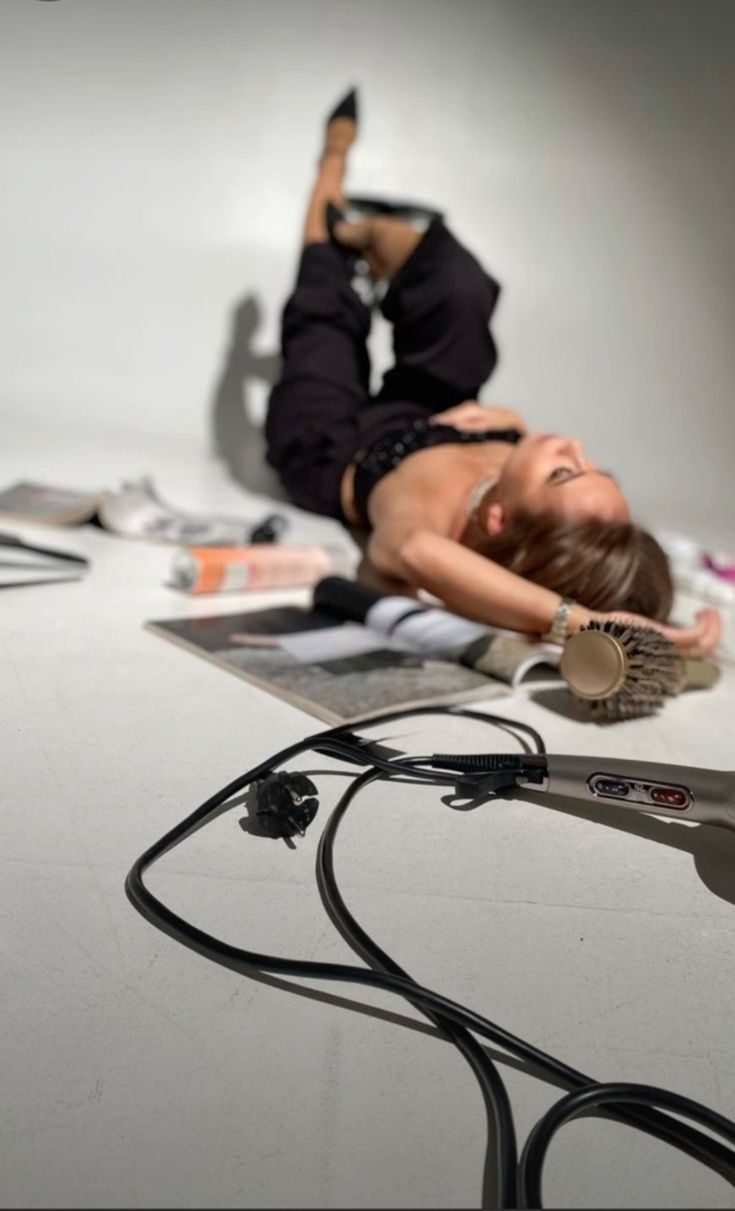 a woman is laying on the floor with her hair dryer in front of her