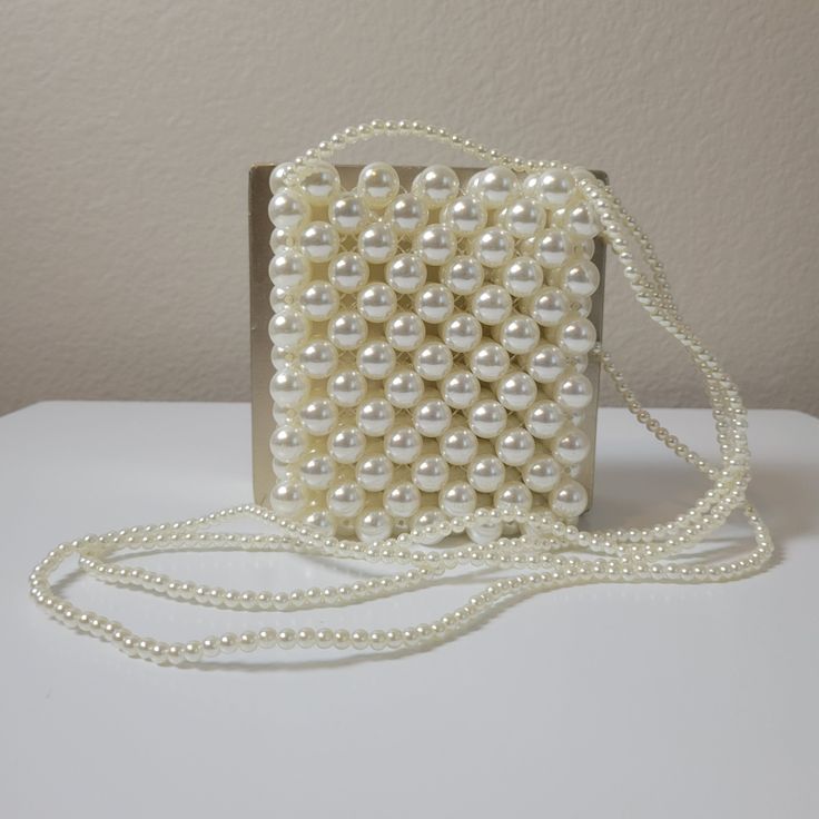 This stunning crossbody handbag is crafted with delicate pearl design and pearl straps. Enjoy effortless style and endless compliments with this elegant bag. Feel beautiful and confident with the perfect accessory for your look. Elegant Cream Crossbody Shoulder Bag, Elegant Phone Bag With Adjustable Strap As Gift, Elegant Shoulder Phone Bag As Gift, Elegant Evening Shoulder Bag With Adjustable Strap, Cream Crossbody Shoulder Bag With Pearl Handle, White Bags With Pearl Chain, Cream Crossbody Clutch For Evening, Evening Cream Crossbody Clutch, White Pearl Bag With Pearl Chain