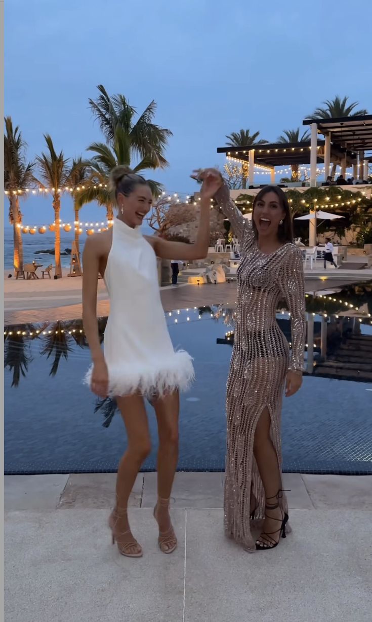 two women standing next to each other near a pool