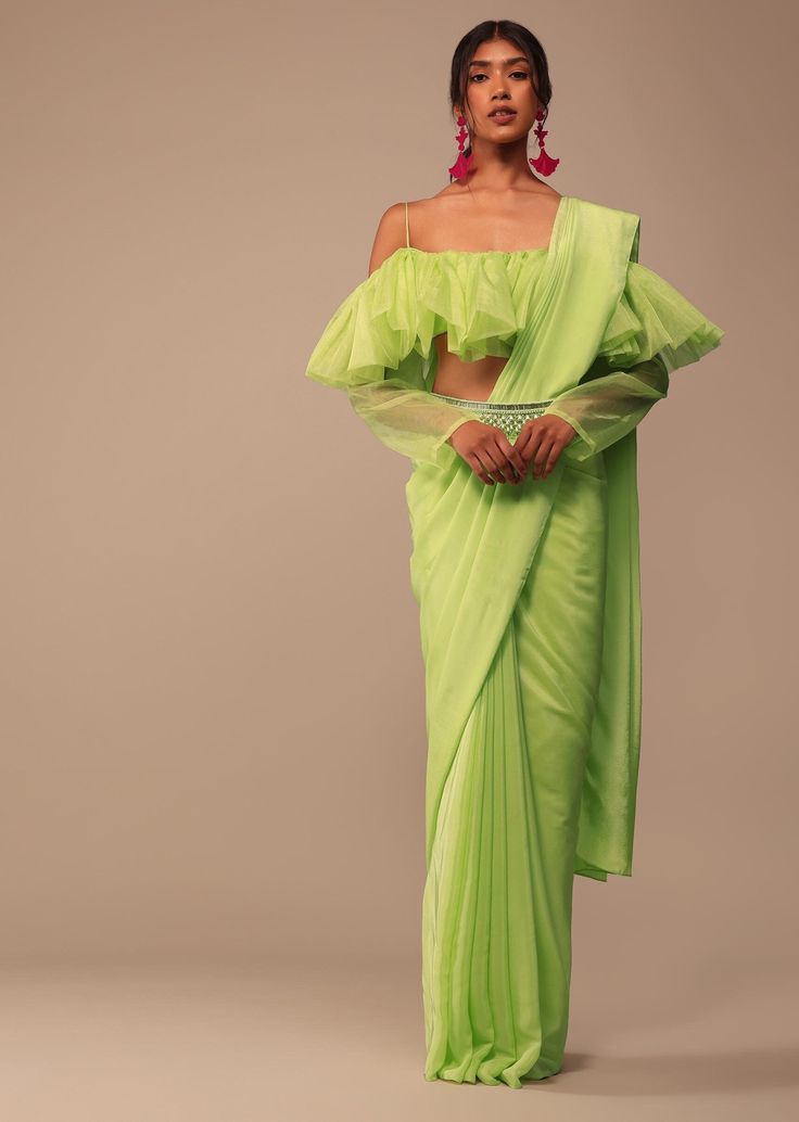 "1. Lite Green Organza Pre-Stitched Saree:- =>Lite Green Color: This refers to the color of the saree. \"Lite Green\" suggests a light or pastel shade of green. =>Organza Fabric: Organza is a thin, sheer fabric known for its silky texture and slight stiffness. It adds an elegant and sophisticated look to the saree. =>Pre-Stitched: A pre-stitched saree means that the pleats are already set, and it might have a pre-attached pallu. This makes it easier to wear, especially for those who may find draping a saree challenging. 2. Organza Frilled Blouse:- =>Organza Fabric: The blouse is made of organza, matching the saree. This creates a cohesive and coordinated look. =>Frilled Design: The term \"frilled\" suggests that the blouse has frills or ruffles as a design element. Frills can add a feminin Ruffle Saree With Belt, Ruffles Saree, Indian Wedding Mehendi, Ramadan 2025, Harmony Tattoo, Boutique Cafe, Wedding Mehendi, Saree With Belt, Indian Sari Dress