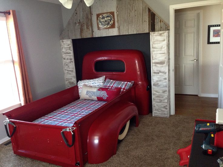 a red truck bed sitting in the middle of a room next to a window with curtains