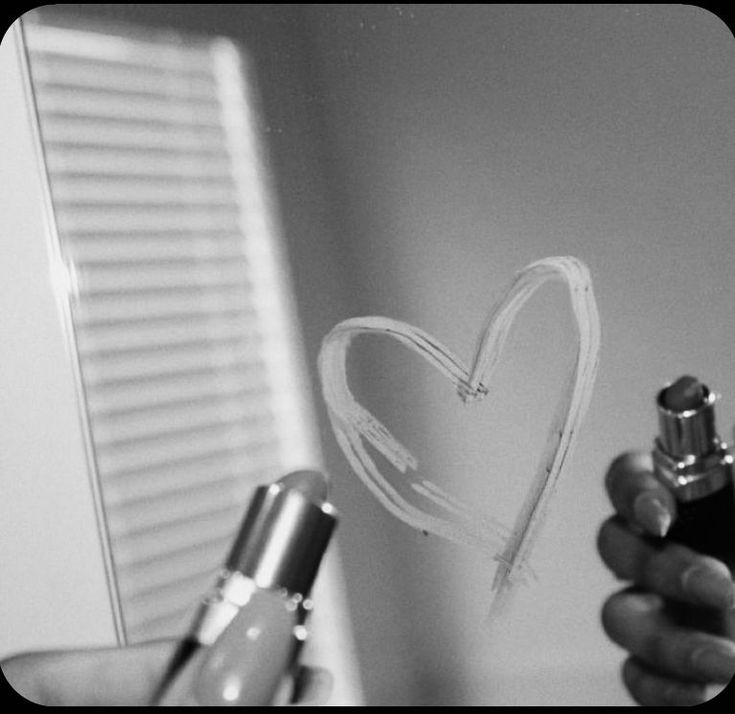 a person holding a pen and drawing a heart on the wall with it's ink