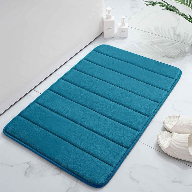 a blue bath mat sitting on top of a bathroom floor