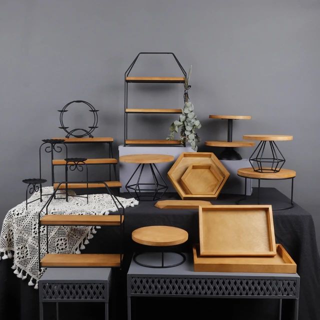 a table topped with lots of wooden plates and trays next to a black table cloth