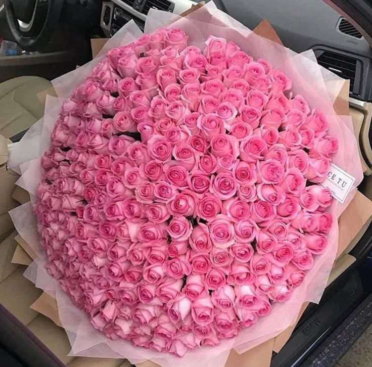 a large bouquet of pink roses sitting on top of a car dashboard