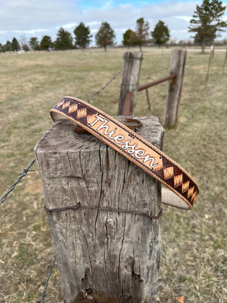 a wooden post with a sign on it near a fence and grass field in the background