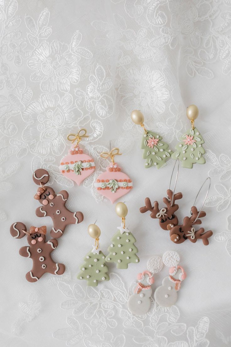 christmas ornaments are arranged on a white lace tablecloth, including gingerbreads and reindeer ornament