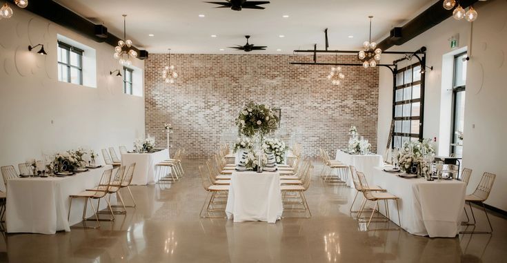 a room filled with lots of tables covered in white linens and flowers on top of them