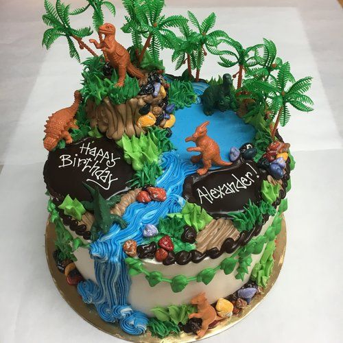 a birthday cake decorated with dinosaurs and trees