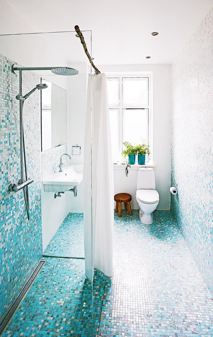 a bathroom with blue and white tiles on the floor, shower, toilet and sink