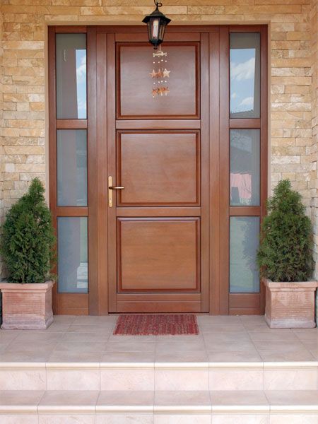 a wooden door with two planters on each side and a light fixture above it