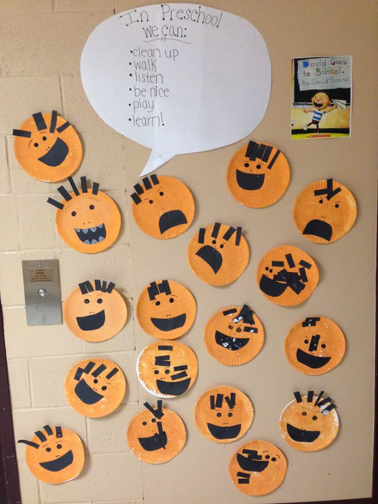 a bulletin board decorated with orange and black paper plates that have faces drawn on them