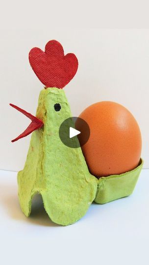 an egg in a carton with a red heart on it's head next to a fake chicken