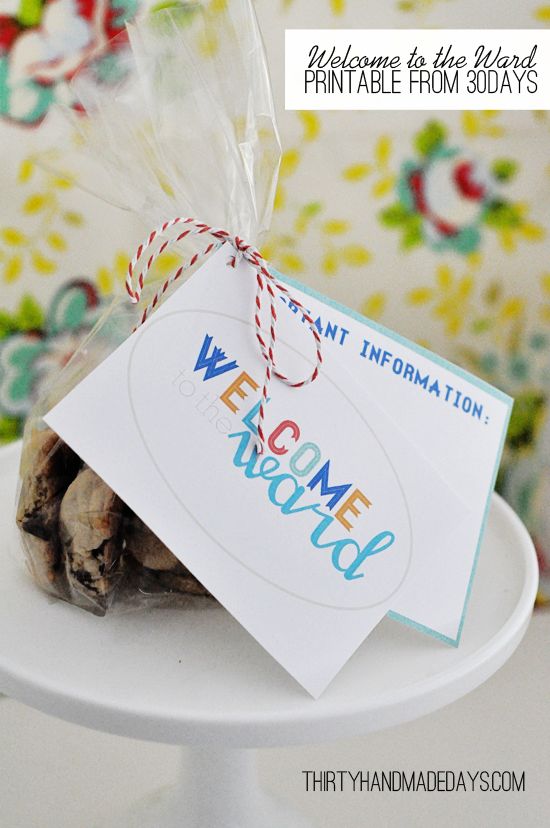 a welcome sign is wrapped in plastic and tied to a white cake plate with colorful flowers