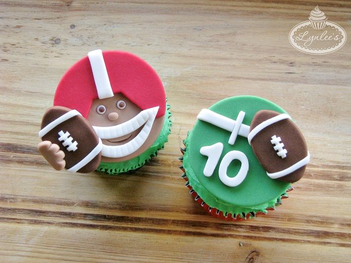 two decorated cupcakes sitting on top of a wooden table