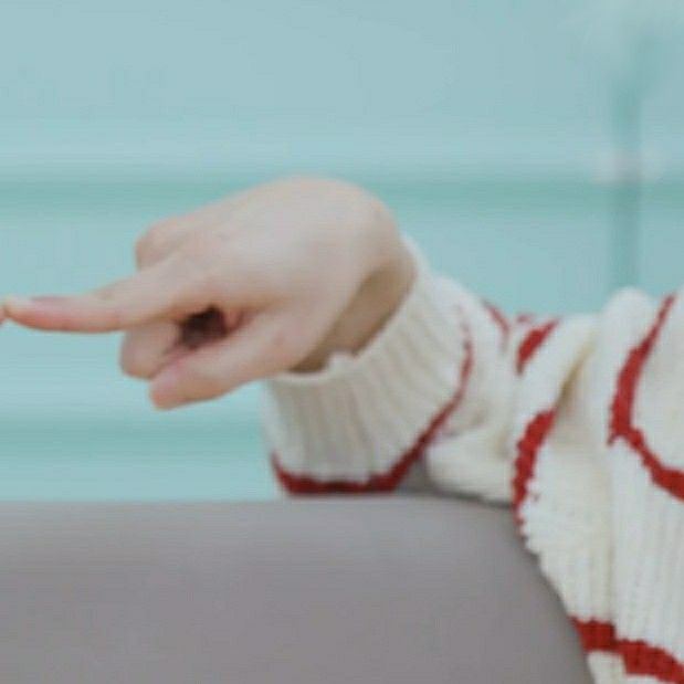 a woman is holding her hand out to the camera while she sits on a couch