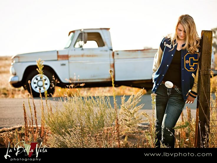 a woman standing in front of an old truck