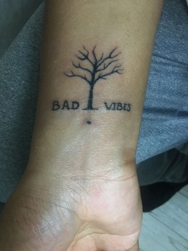 a person's wrist with a tattoo on it that says bad vibes and a tree