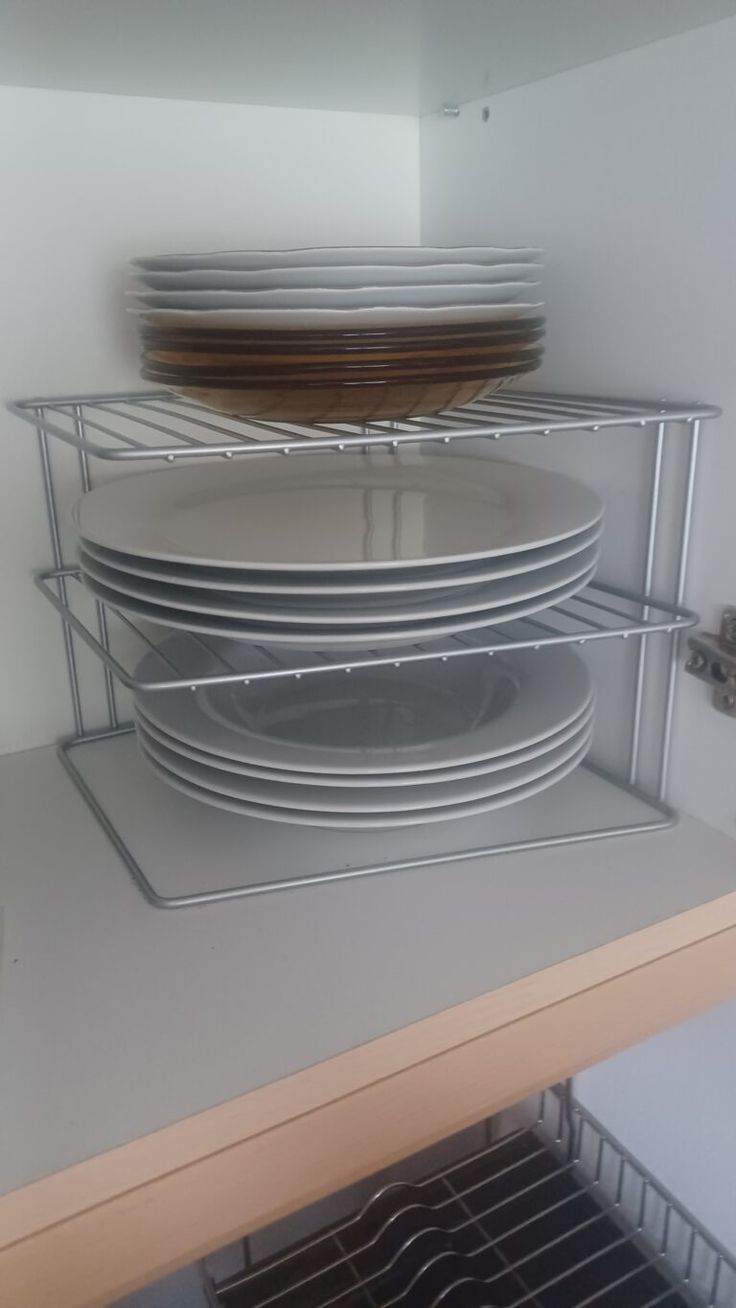 several plates stacked on top of each other in a kitchen cabinet with wire racking