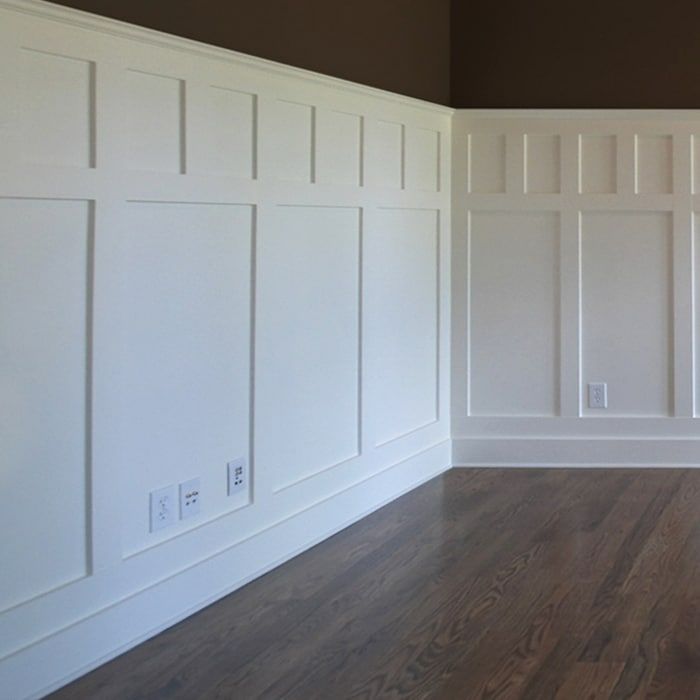 an empty room with white paneling and wood floors