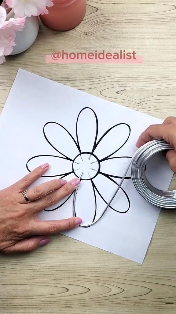 someone is making a flower out of paper with scissors and some tape on the table