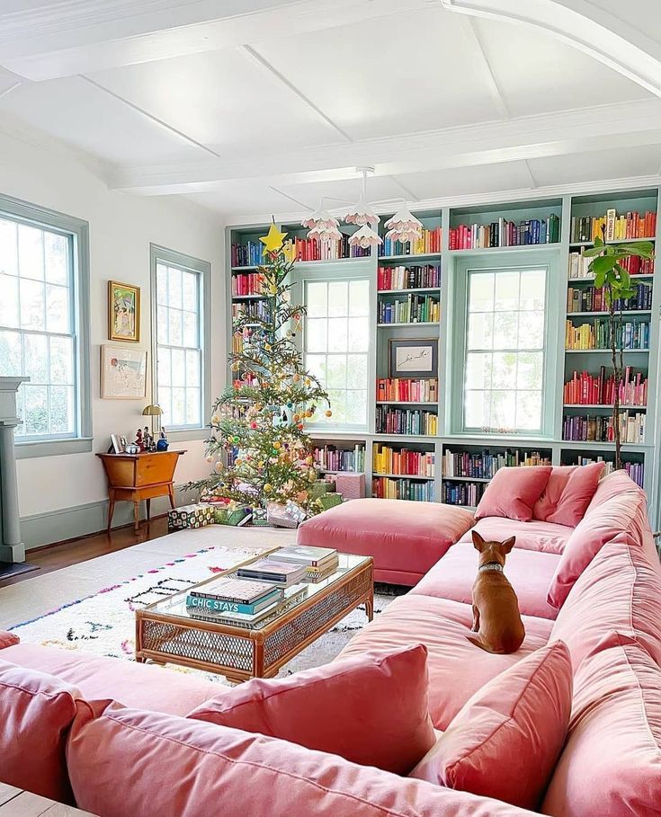 a living room with pink couches and a christmas tree