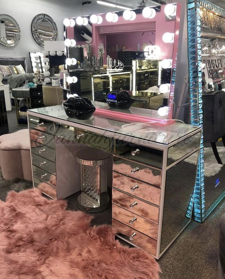 a vanity table with a mirror and lights on it in a room filled with furniture