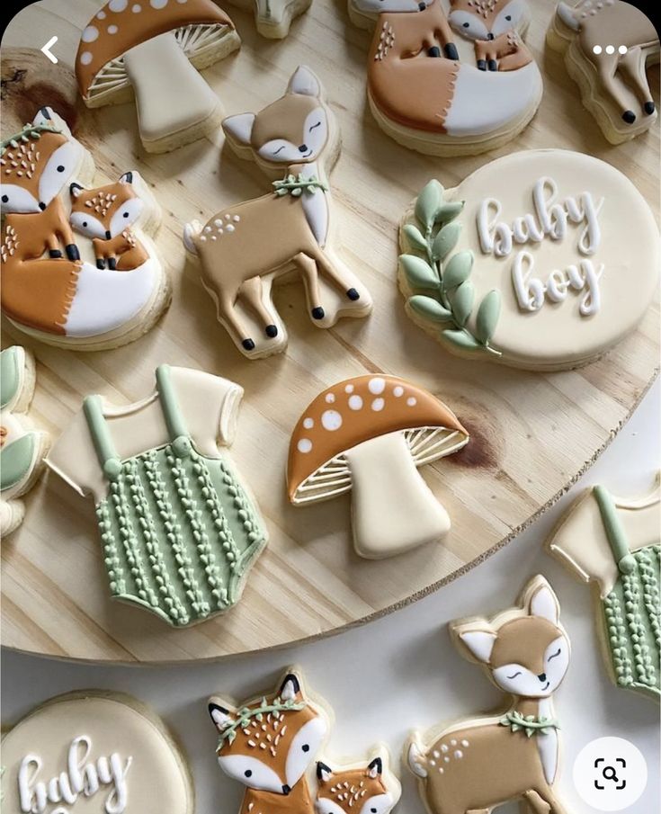 baby boy cookies decorated with woodland animals on a wooden platter and surrounded by forest decorations