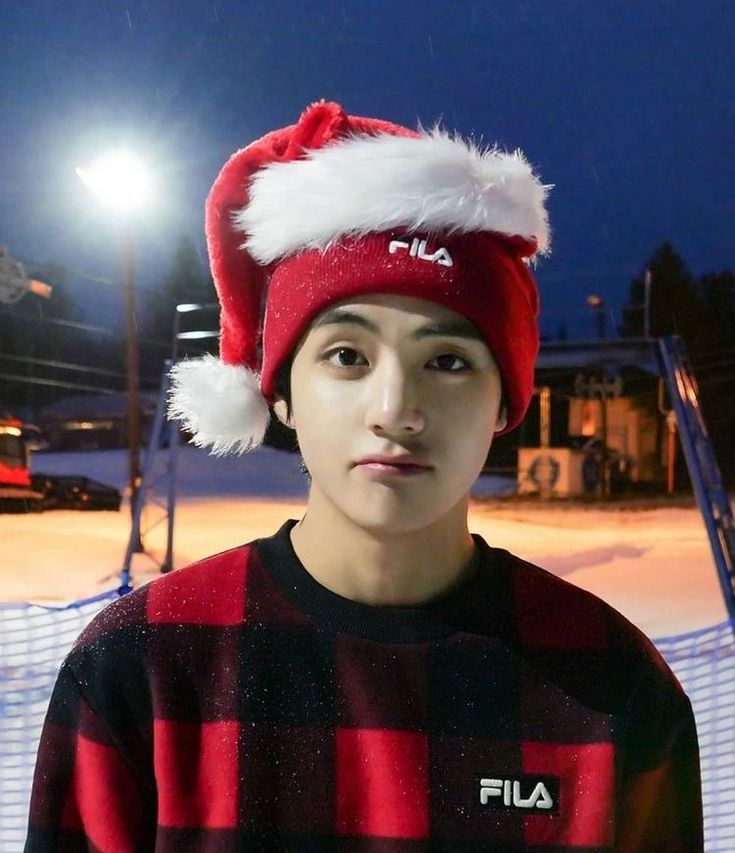 a young man wearing a red and black sweater with a santa hat on his head