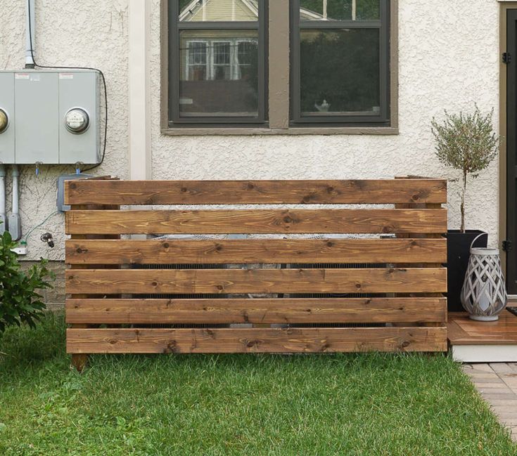 a wooden bench sitting in front of a house next to a planter filled with flowers