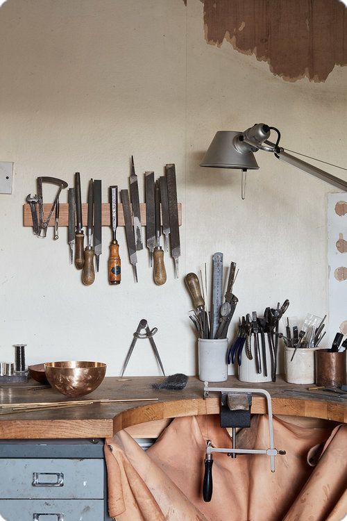 a kitchen counter with many knives and spoons hanging on the wall above it,