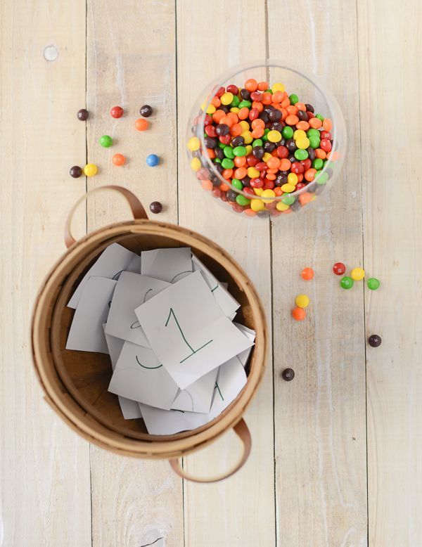 a bowl filled with lots of different colored candies next to a container full of cards