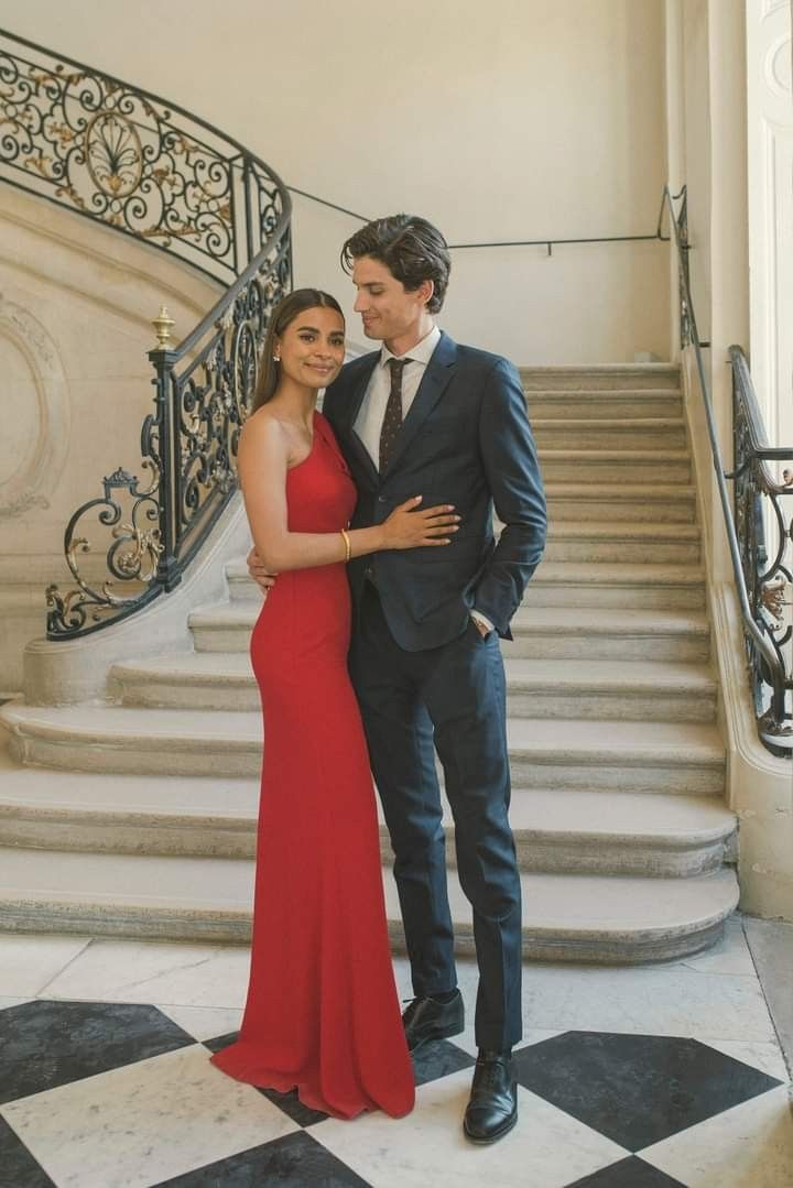 a man in a suit and woman in a red dress standing next to some stairs