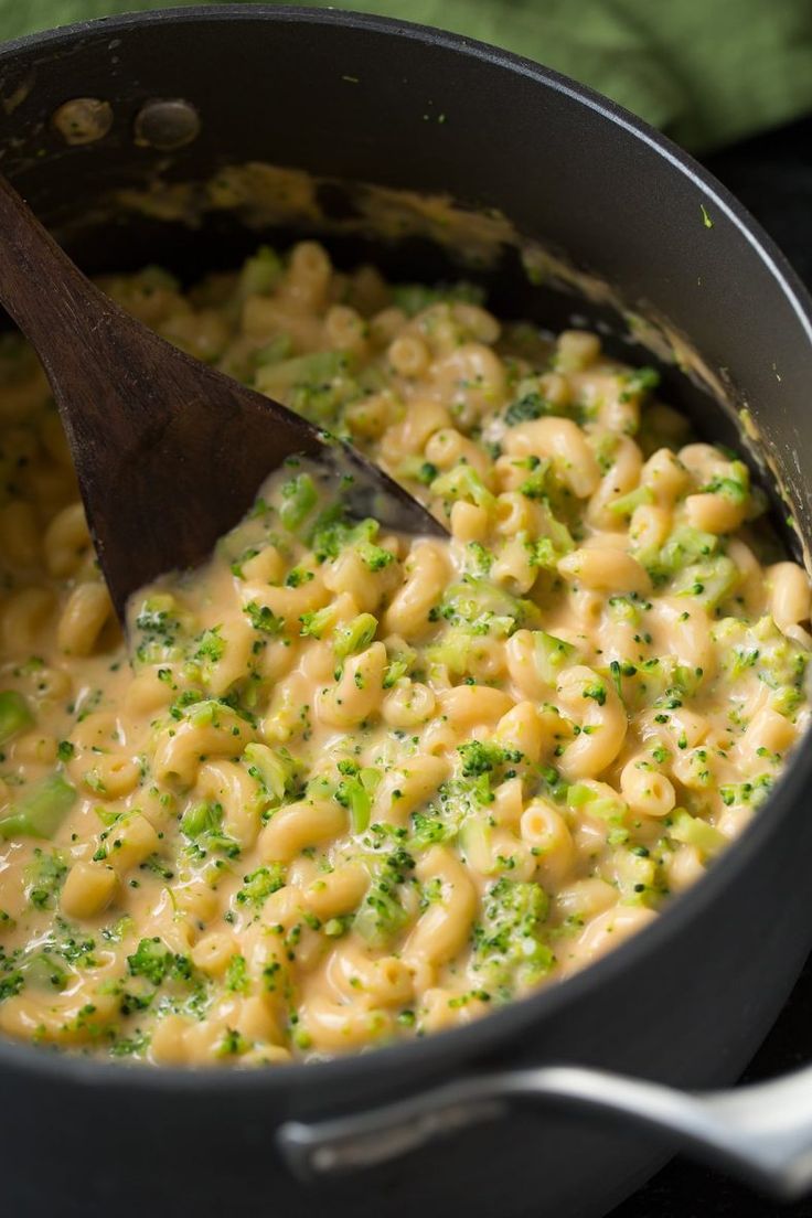 broccoli macaroni and cheese in a pot with a wooden ladle