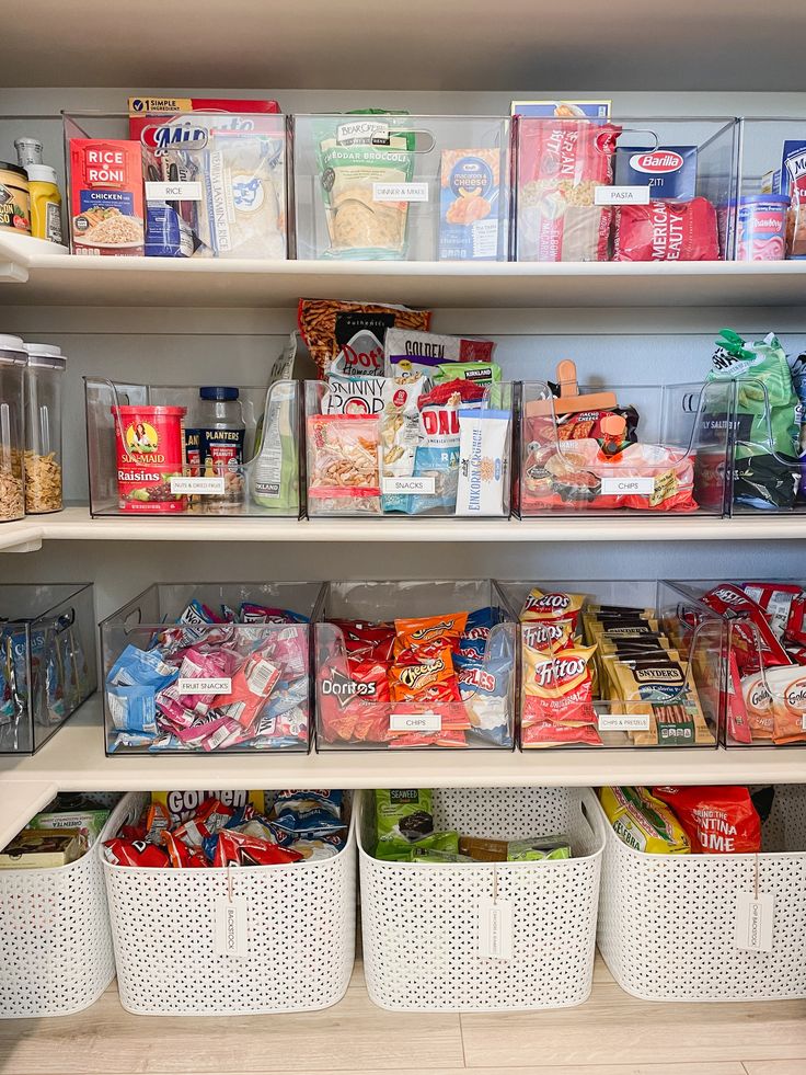 an organized pantry with plastic bins and baskets on the bottom shelf filled with food