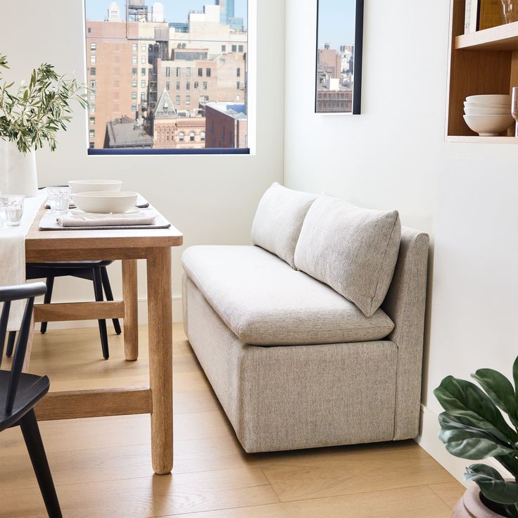 a couch sitting in front of a window next to a table with plates on it