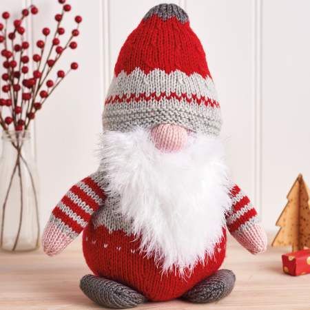 a knitted santa clause doll sitting on top of a wooden table