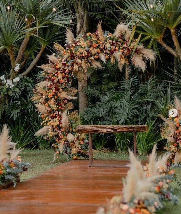 an outdoor ceremony with flowers and greenery on the ground, surrounded by palm trees