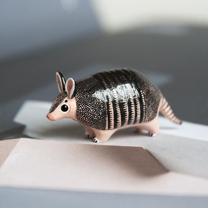 a small toy armadile sitting on top of a piece of white paper with black spots