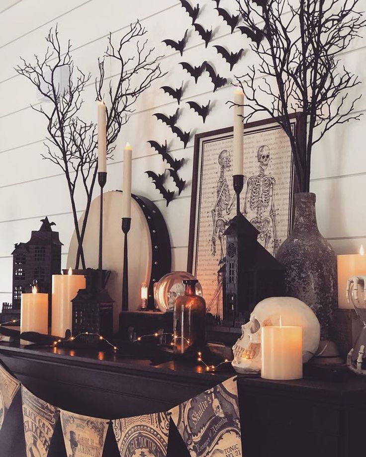 a mantle with candles and decorations on it in front of a wall decorated with bats