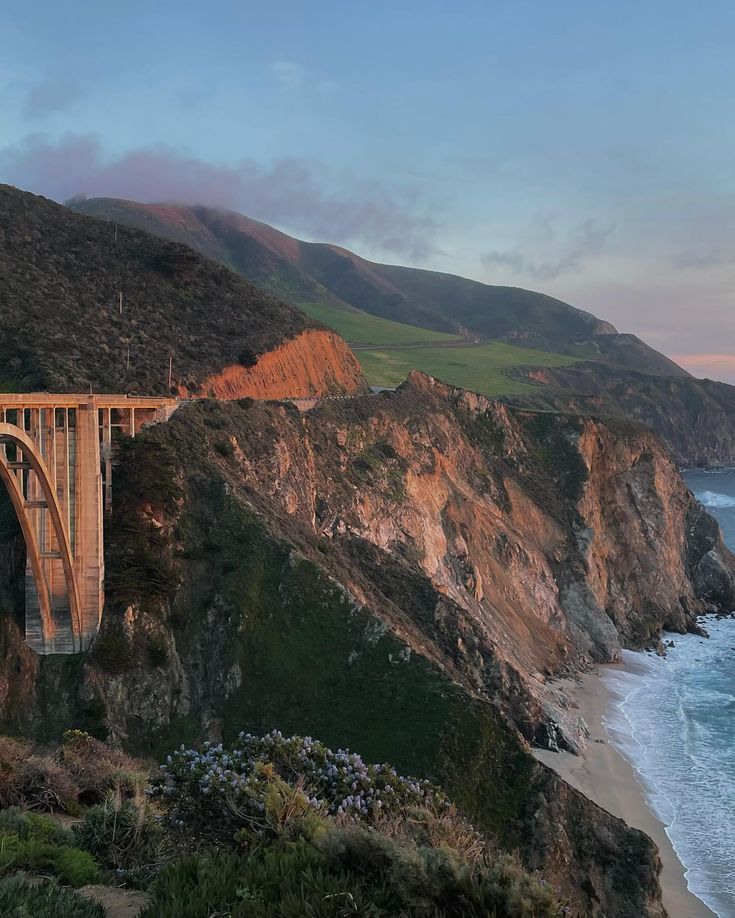 a large bridge spanning over the ocean next to a cliff