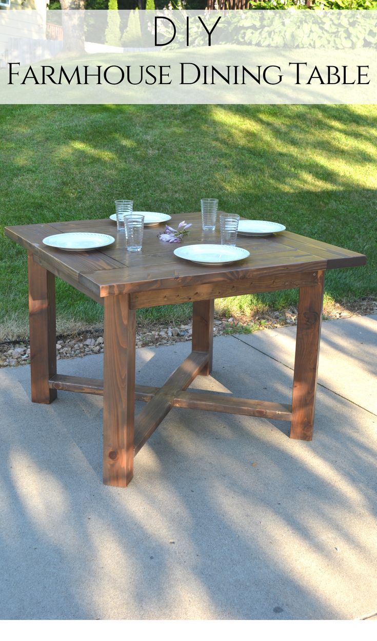 a wooden table with plates and glasses on it in the middle of a lawn area