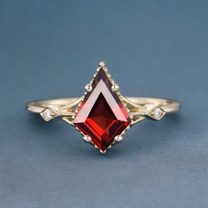 a gold ring with a red stone in the center and two diamonds on each side