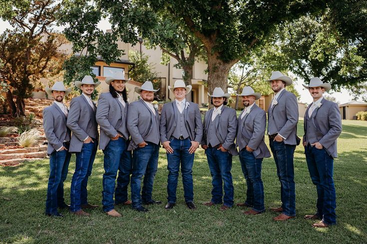 a group of men in suits and hats standing next to each other on the grass